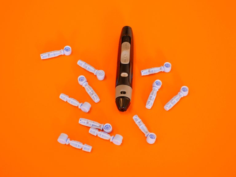 Glucomètre et lancettes sur fond orange