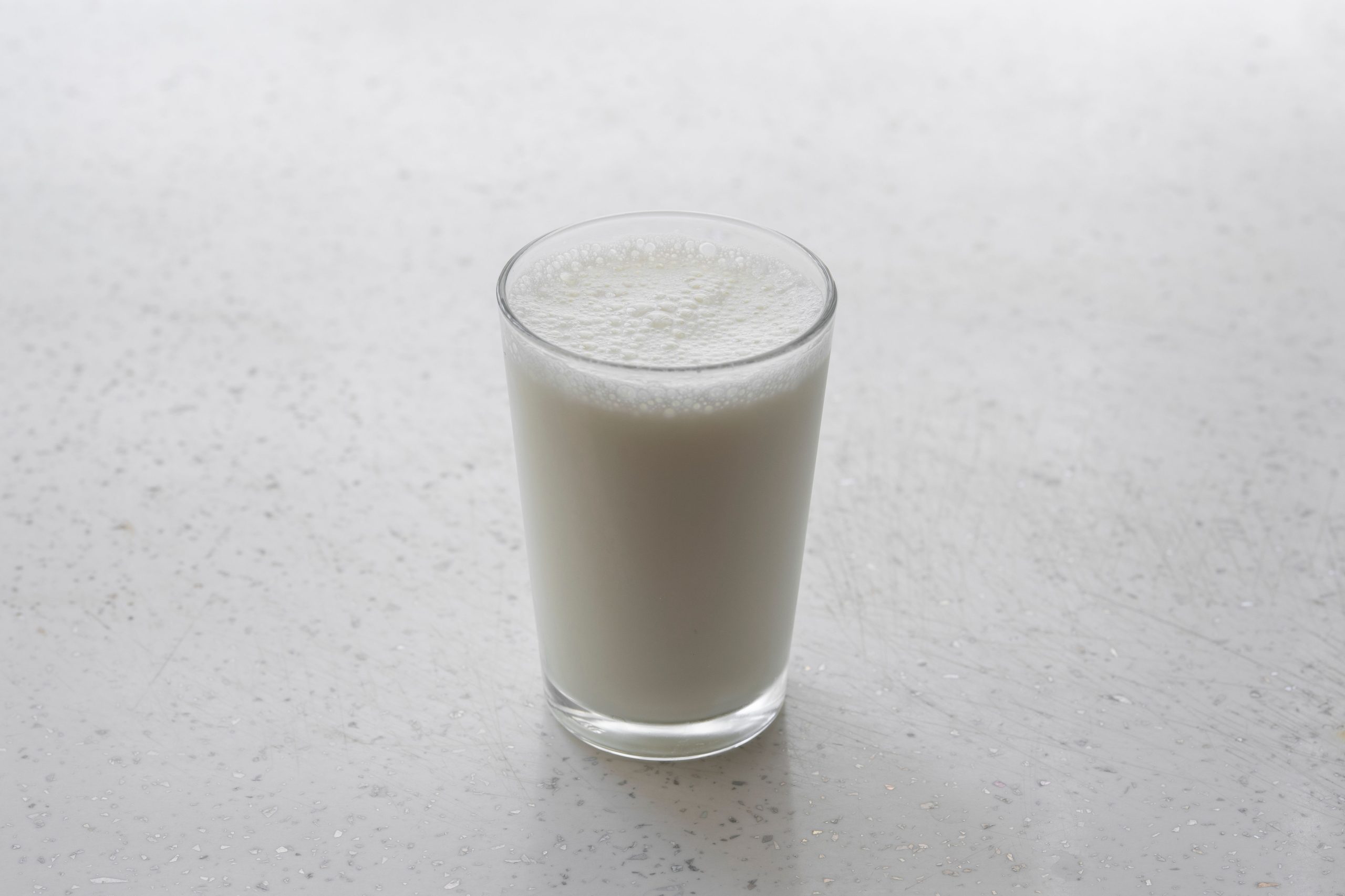 Verre de lait mousseux surface texturee blanche