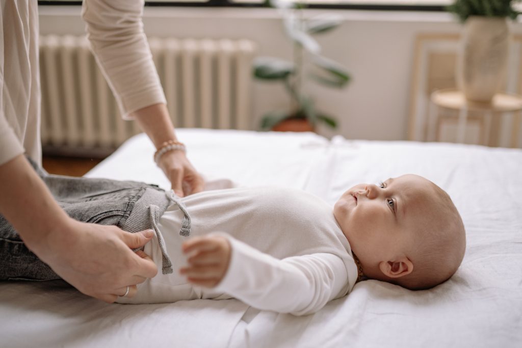Mère habille tendrement son bébé sur lit