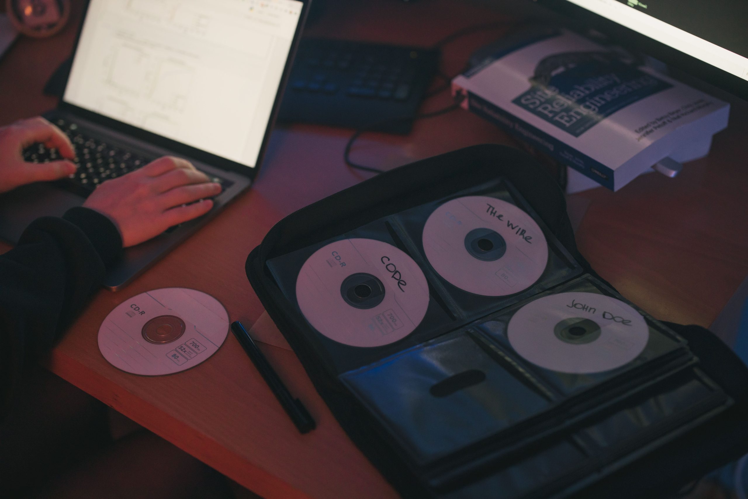 Personne travaillant sur ordinateur avec CDs étiquetés