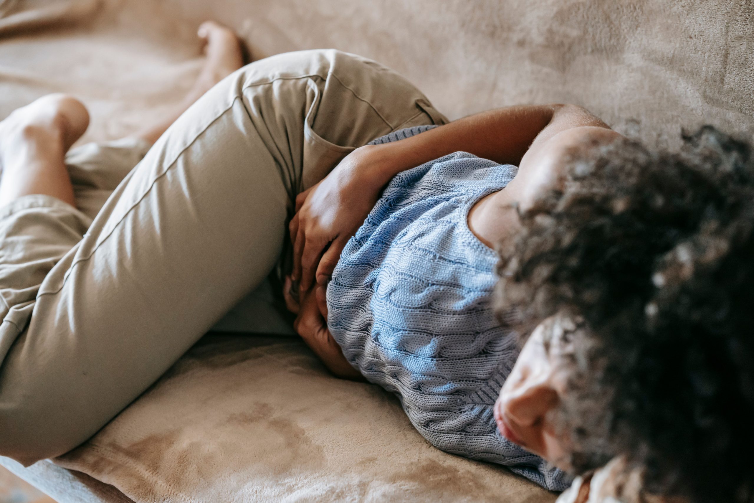 Femme allongée se touchant le ventre avec inconfort
