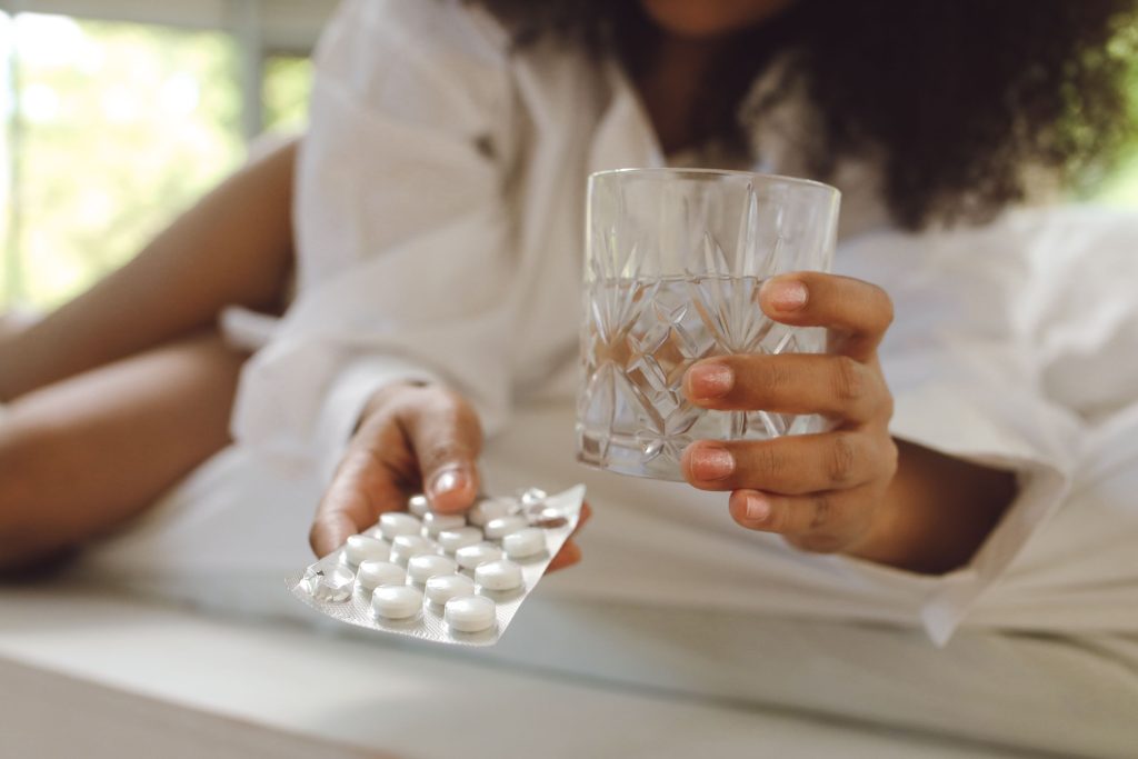 Femme tenant un verre d'eau et son médicament