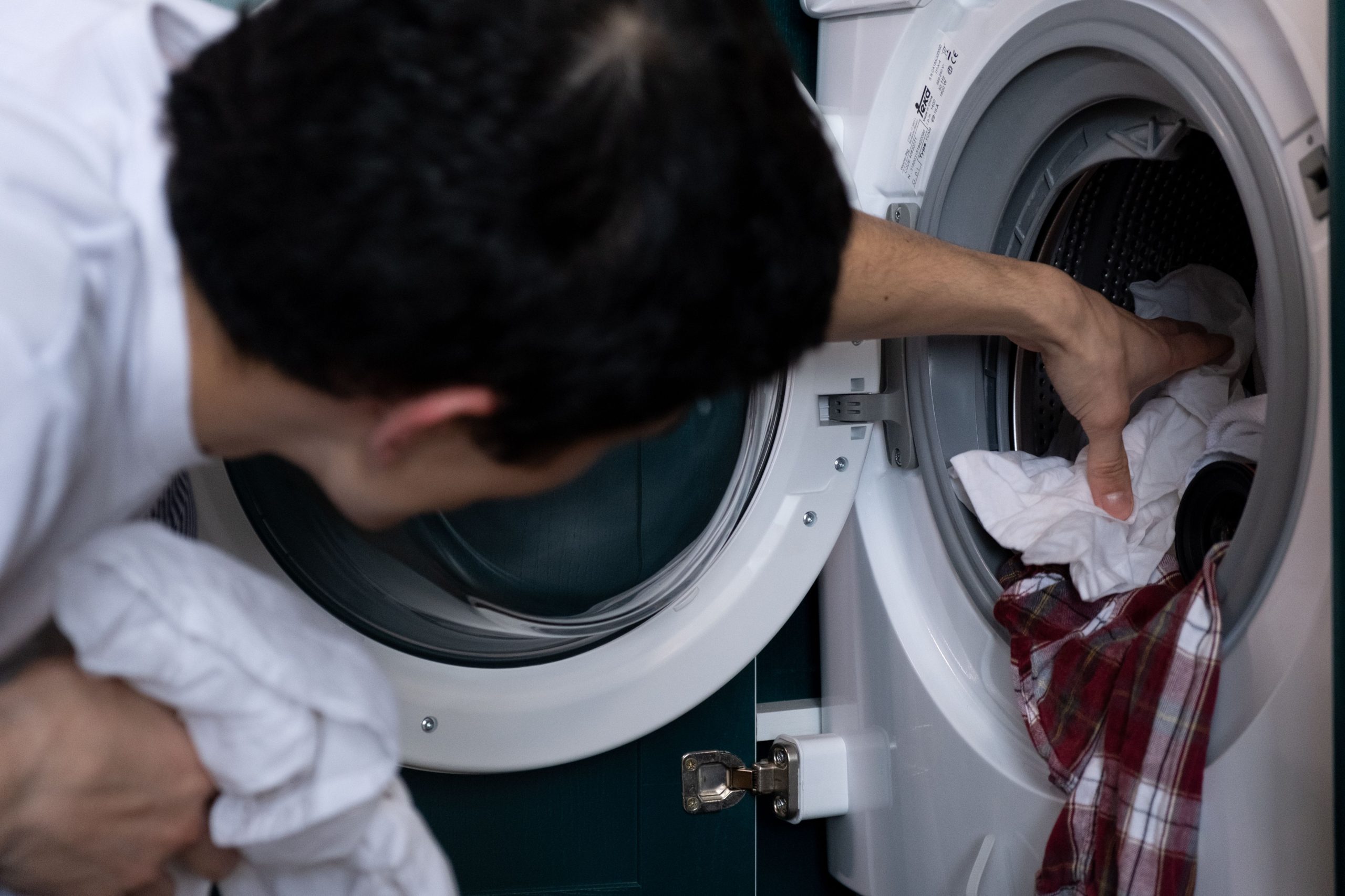 Homme plaçant vêtements dans lave-linge