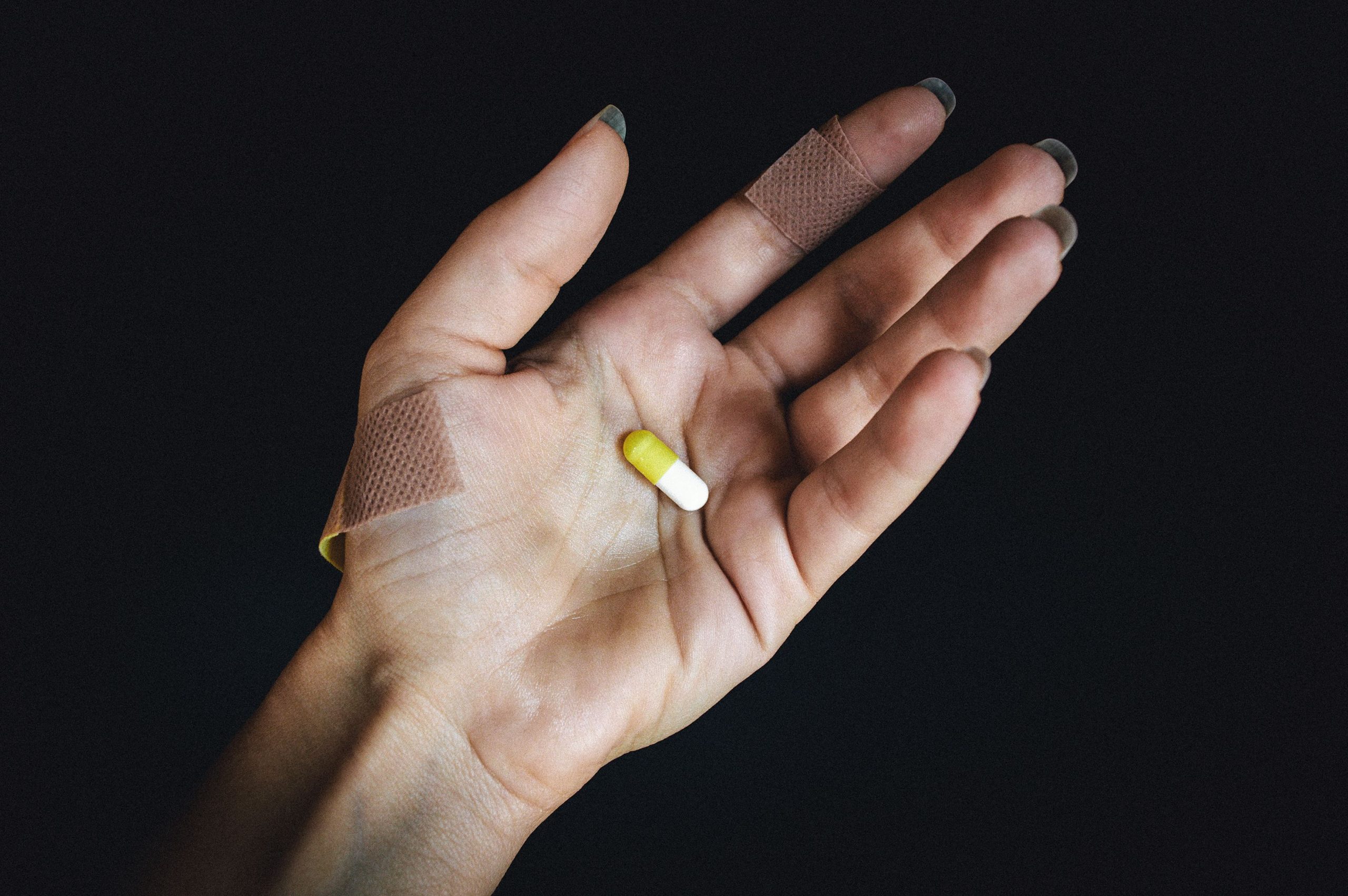 Main avec pansements tenant capsule medicale