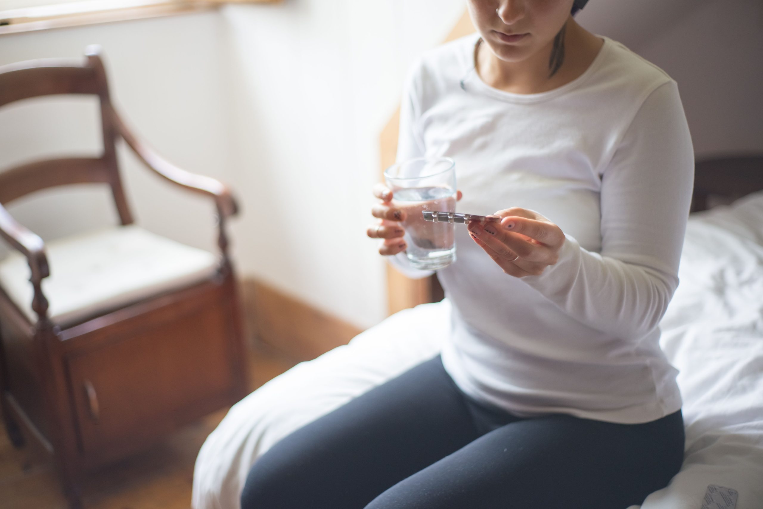 Femme assise prenant son médicament avec eau