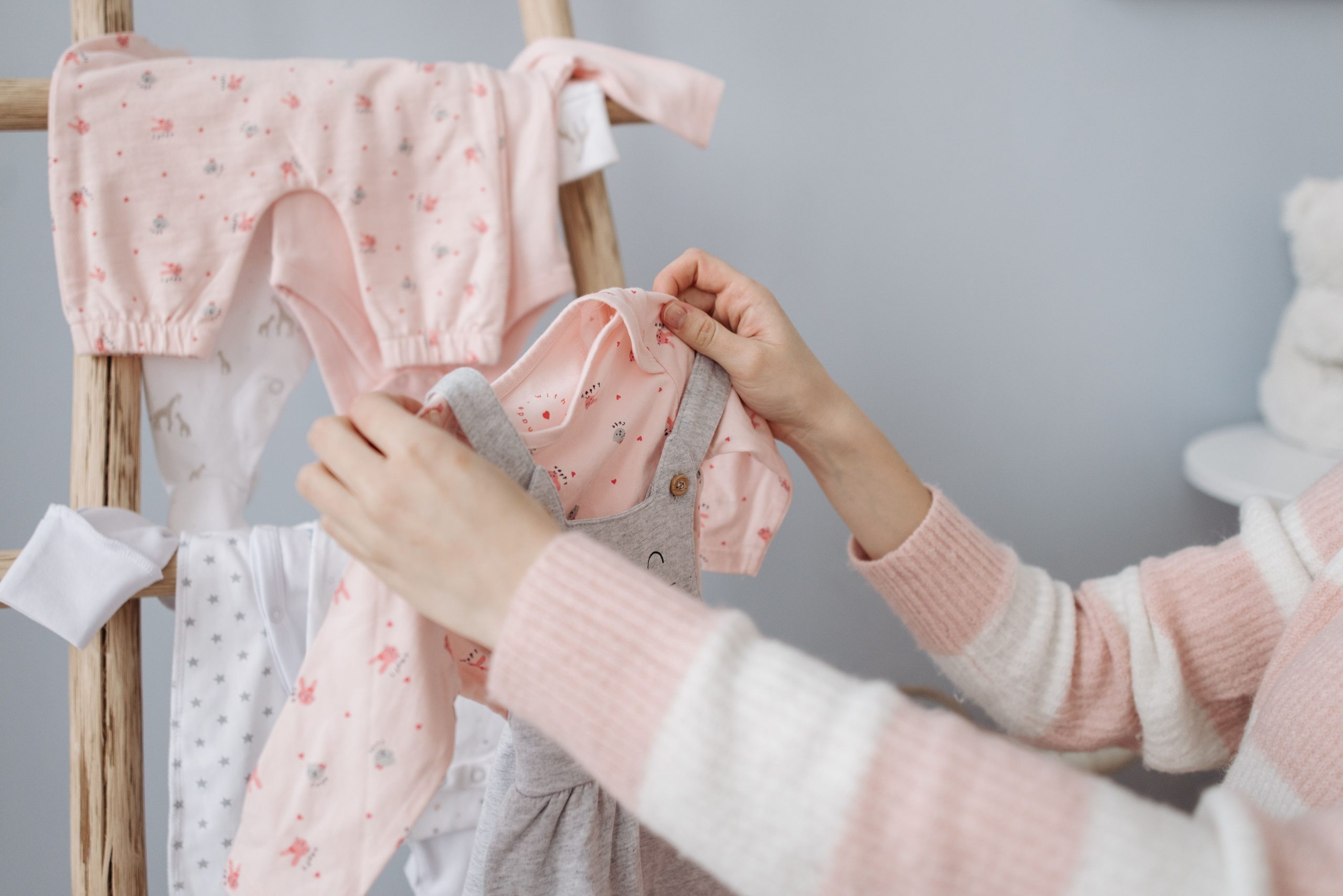 Mère organise vêtements bébé sur portant