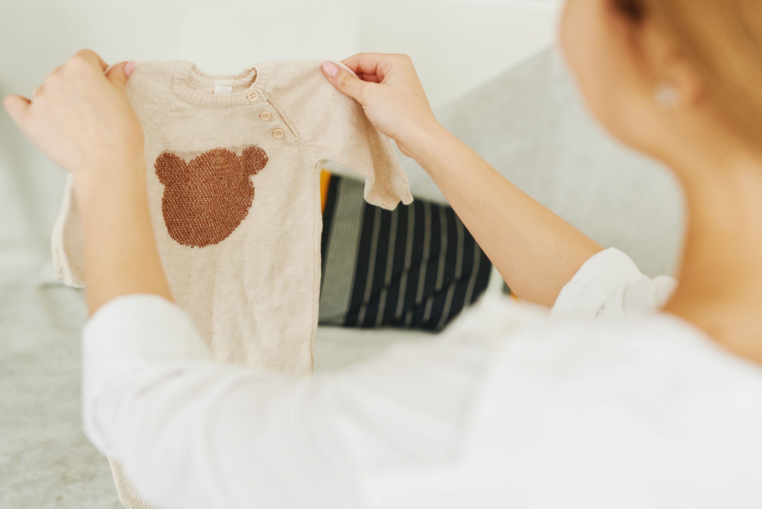 Femme examine pull bébé design ours
