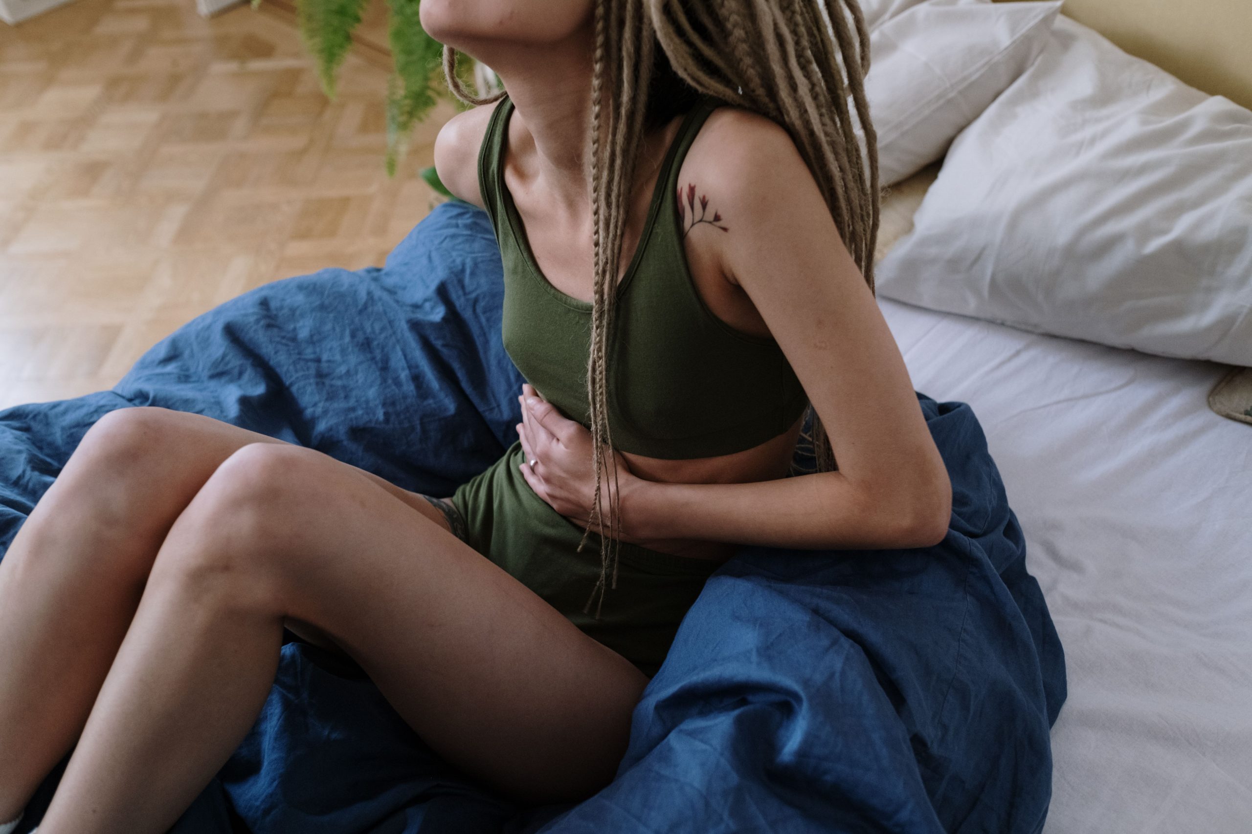 Femme au lit se tenant le ventre douloureux