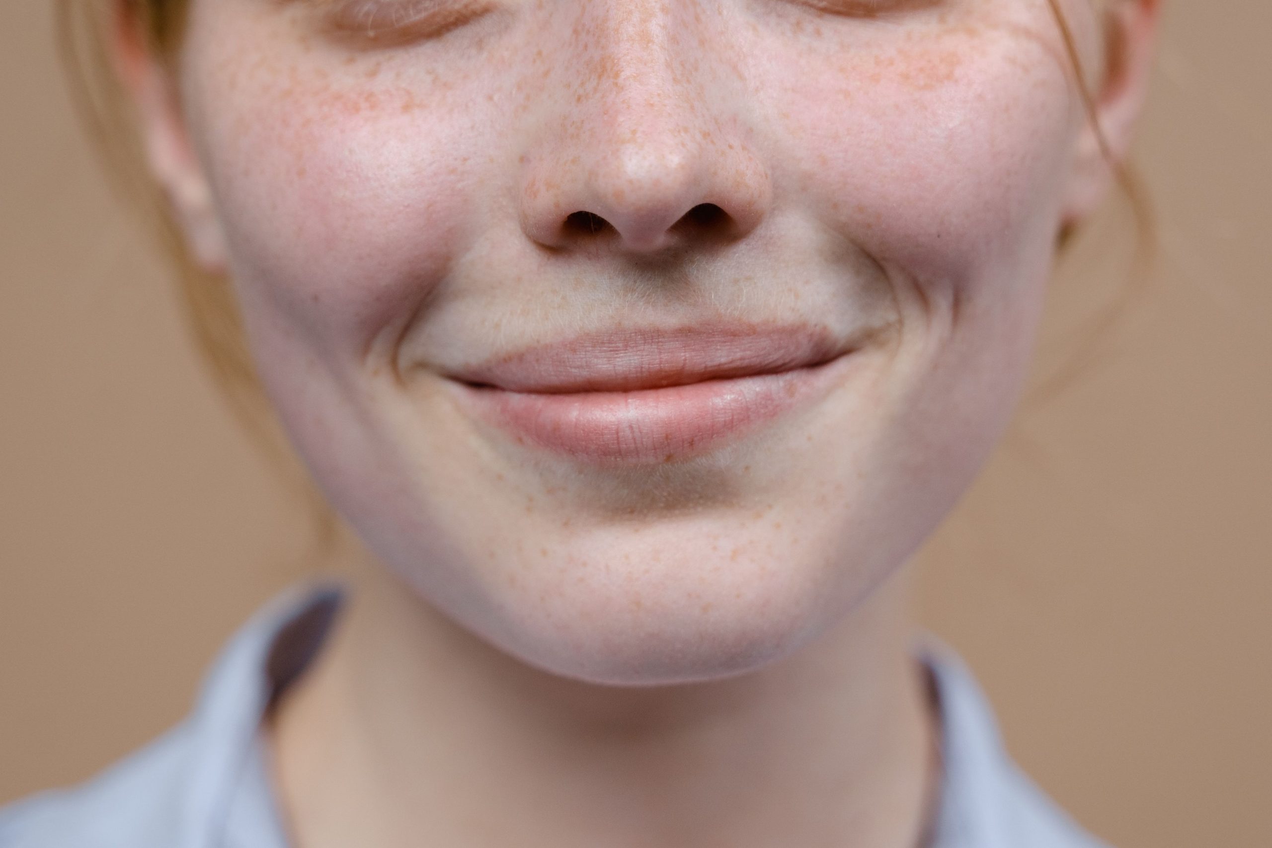 Gros plan sur un sourire discret et taches de rousseur