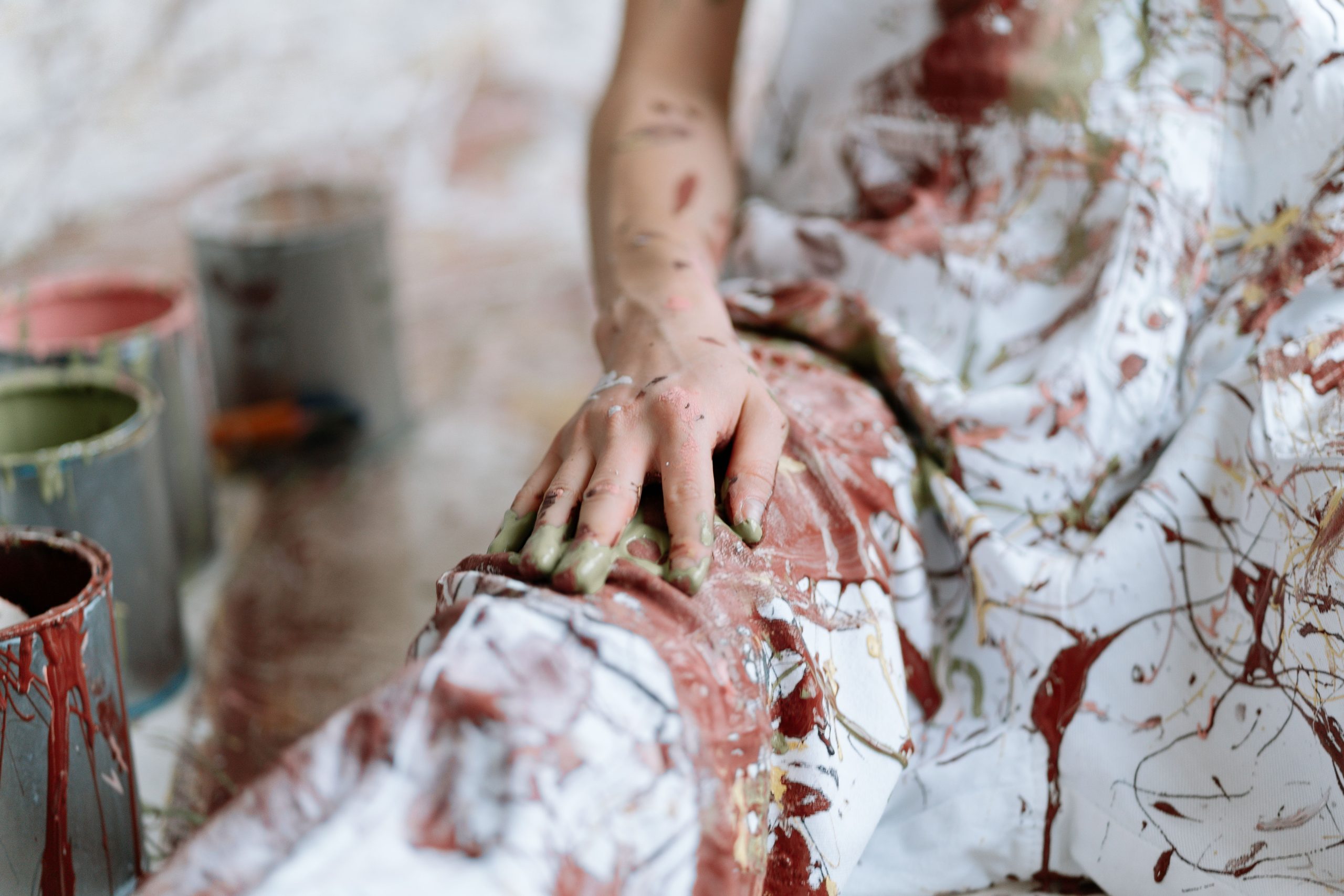 Main tachée de peinture près de pots de couleur