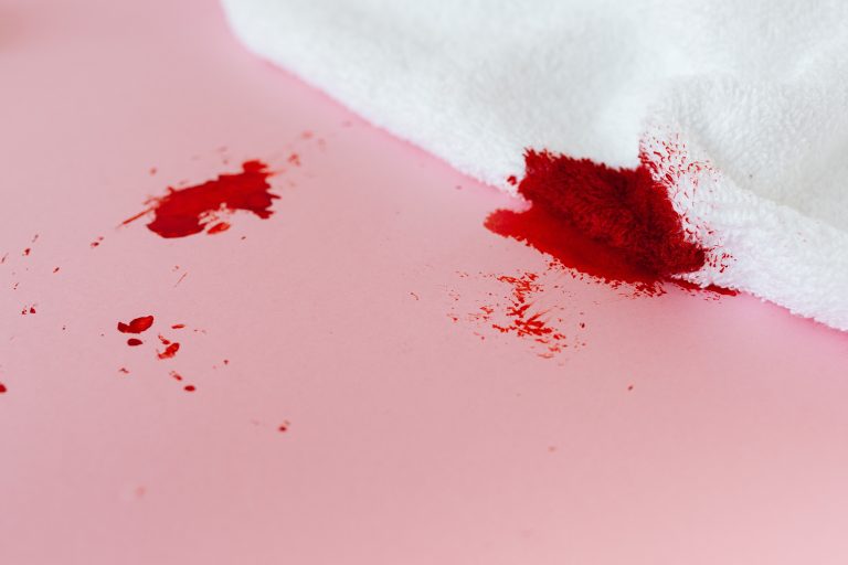 Tissu blanc taché de peinture rouge sur fond rose