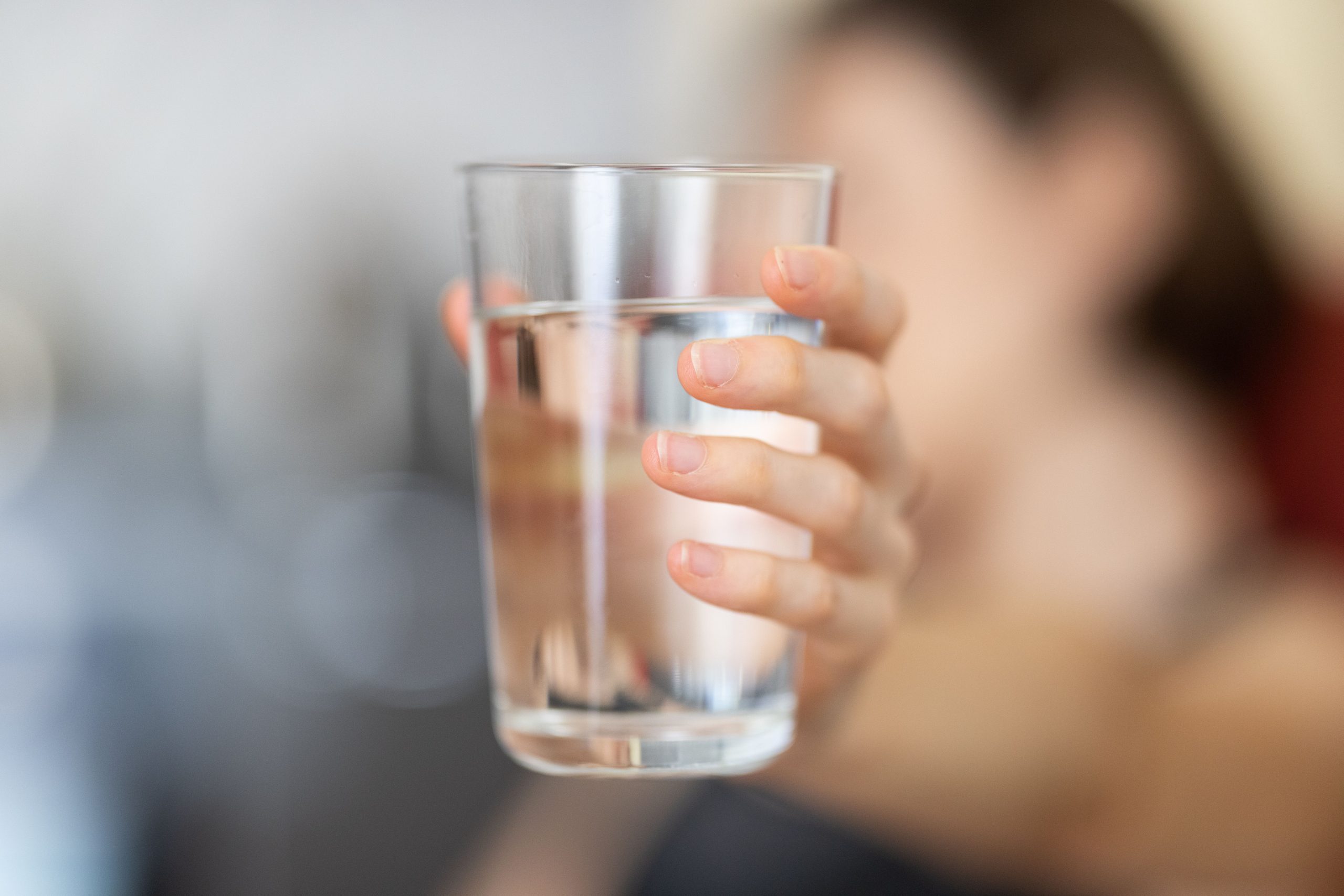 Main tenant un verre d'eau transparent